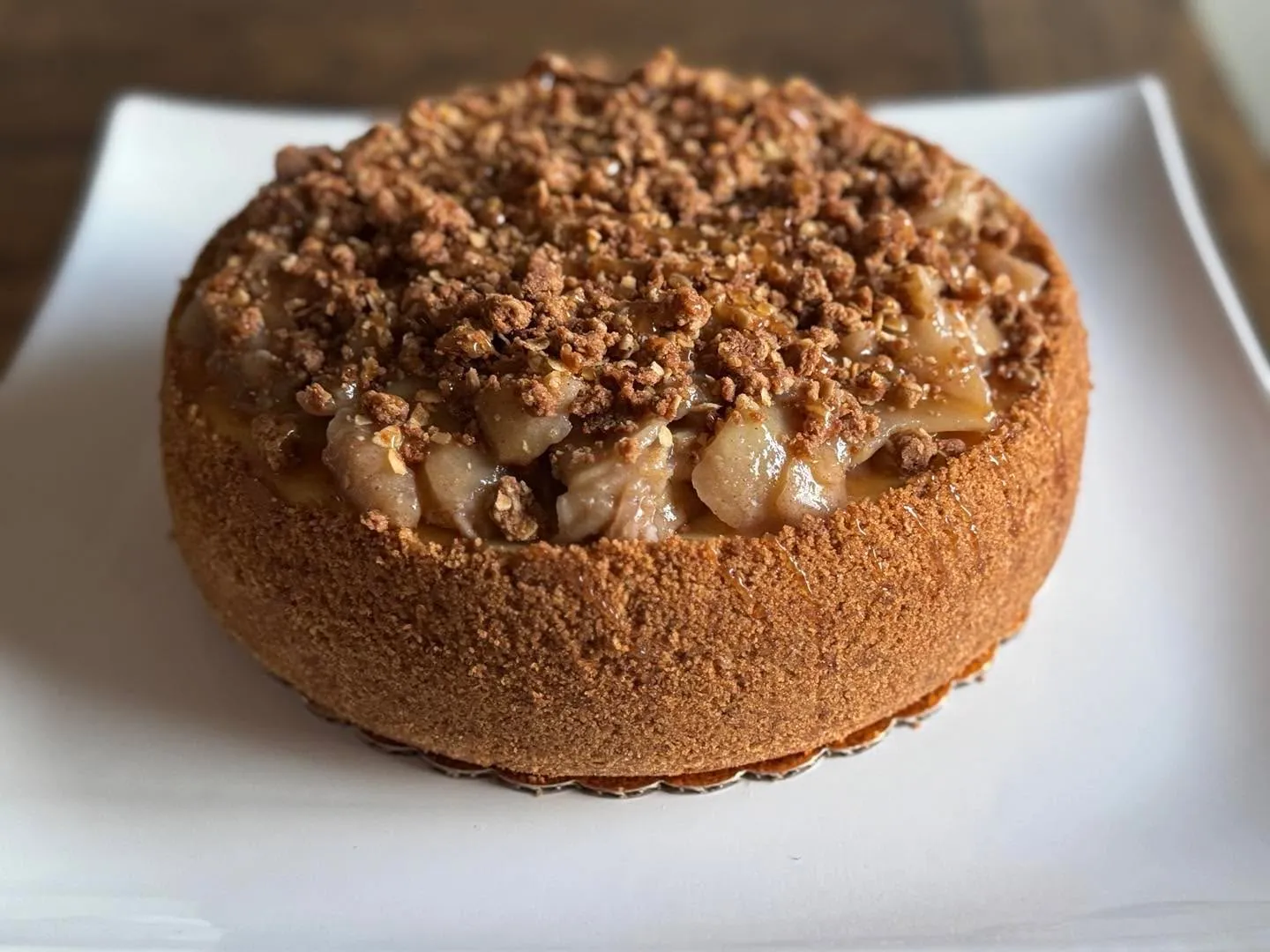 An apple crumble cheesecake topped with caramel apples and cinnamon-oat streusel.