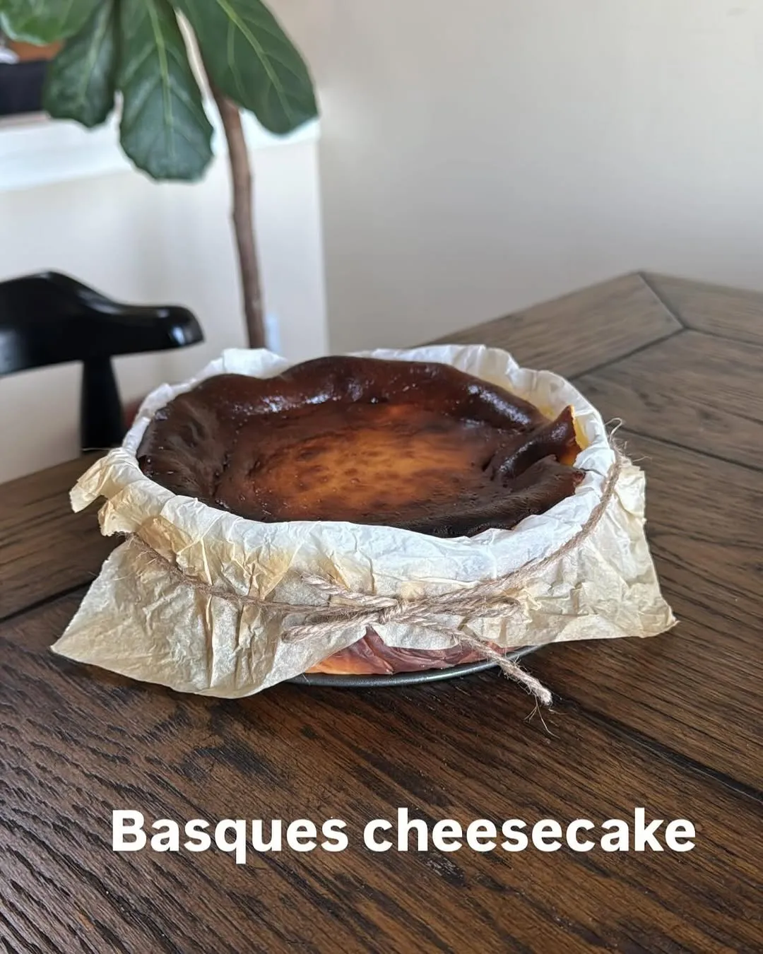 A burnished, crustless Basque cheesecake baked in crumpled parchment paper tied with twine.