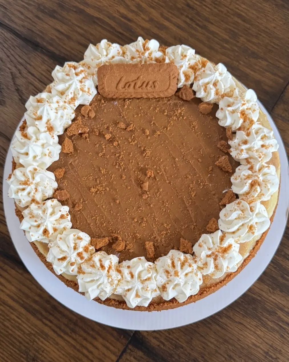 A Biscoff cheesecake with a caramel-coloured top, a Lotus biscuit in the centre and whipped-cream rosettes.
