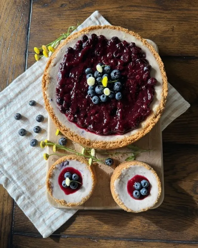 A blueberry cheesecake served with two mini blueberry cheesecakes.