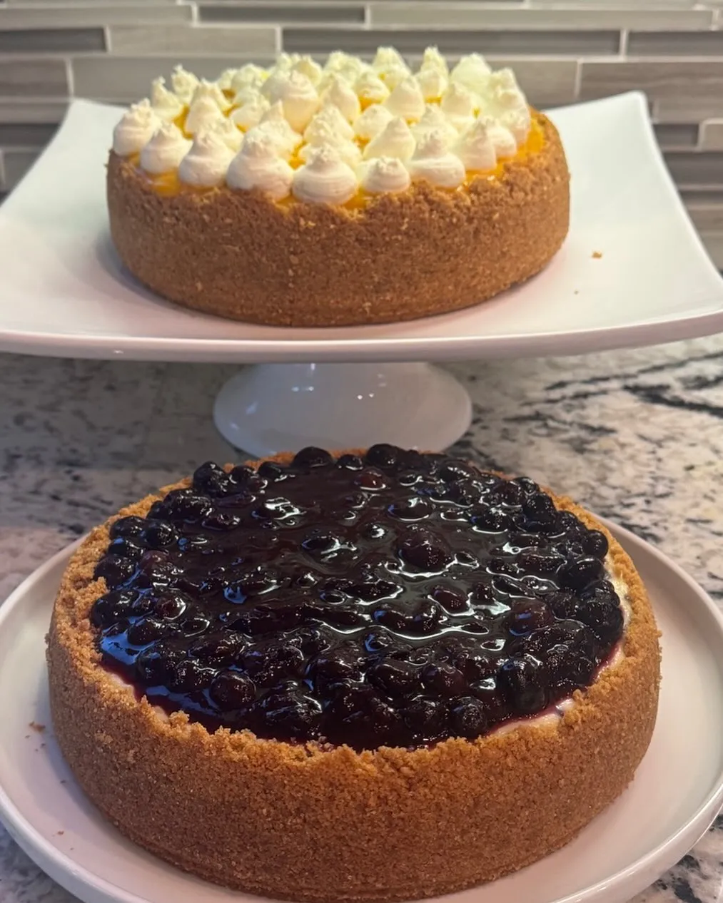 A mango cheesecake and a blueberry cheesecake side by side.