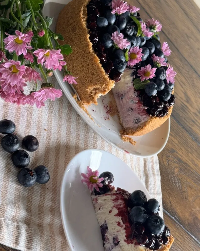 A mango cheesecake and a blueberry-compote cheesecake on white serving plates.