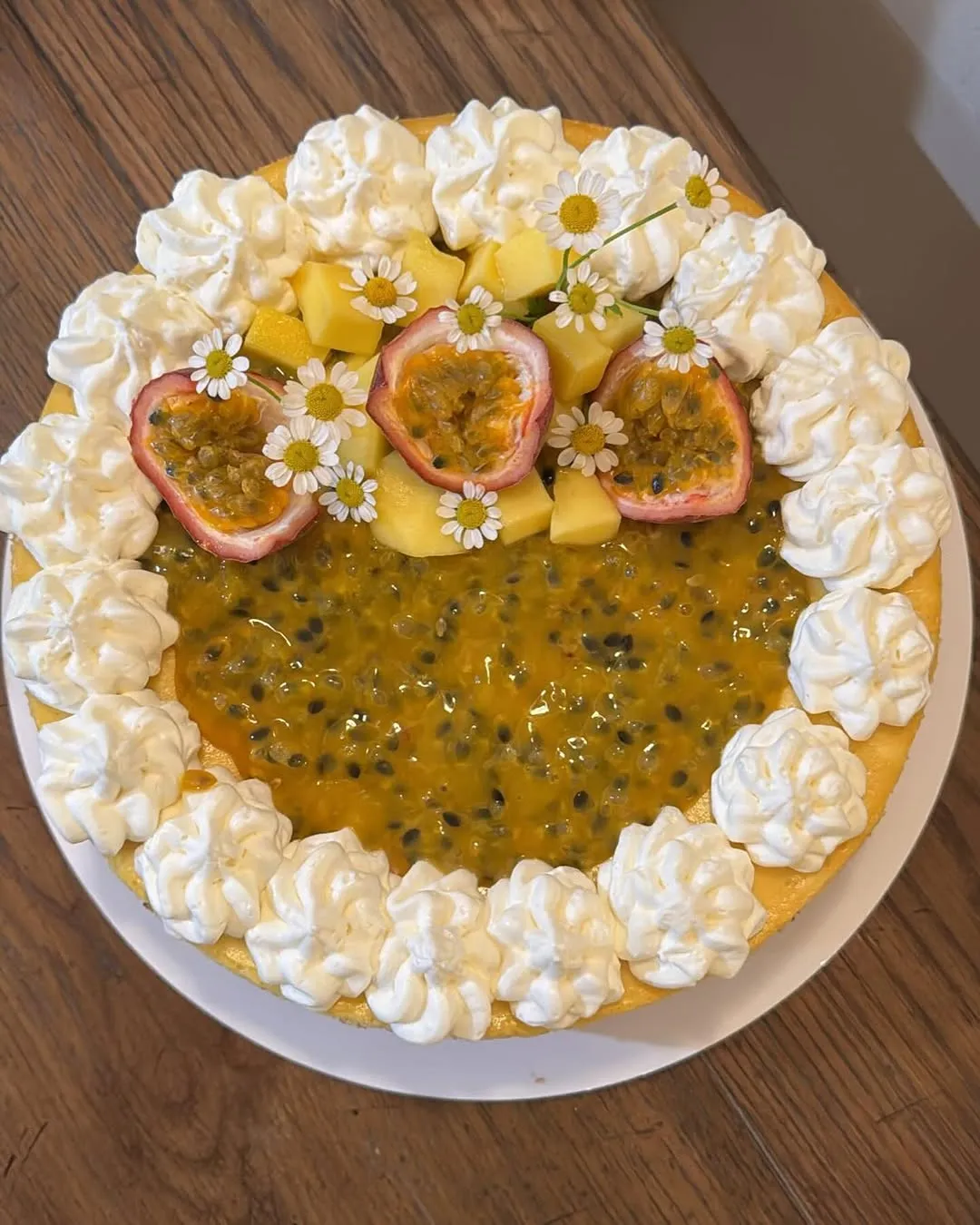 A cheesecake topped with passion-fruit pulp, fresh mango chunks and halved passion fruits.