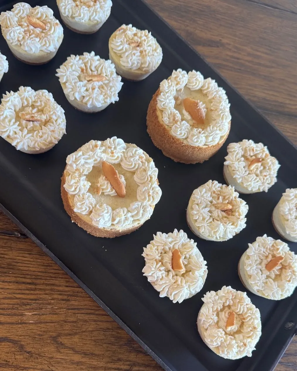 A tray of mini cheesecakes topped with whipped-cream swirls and a sliver of toasted nut.