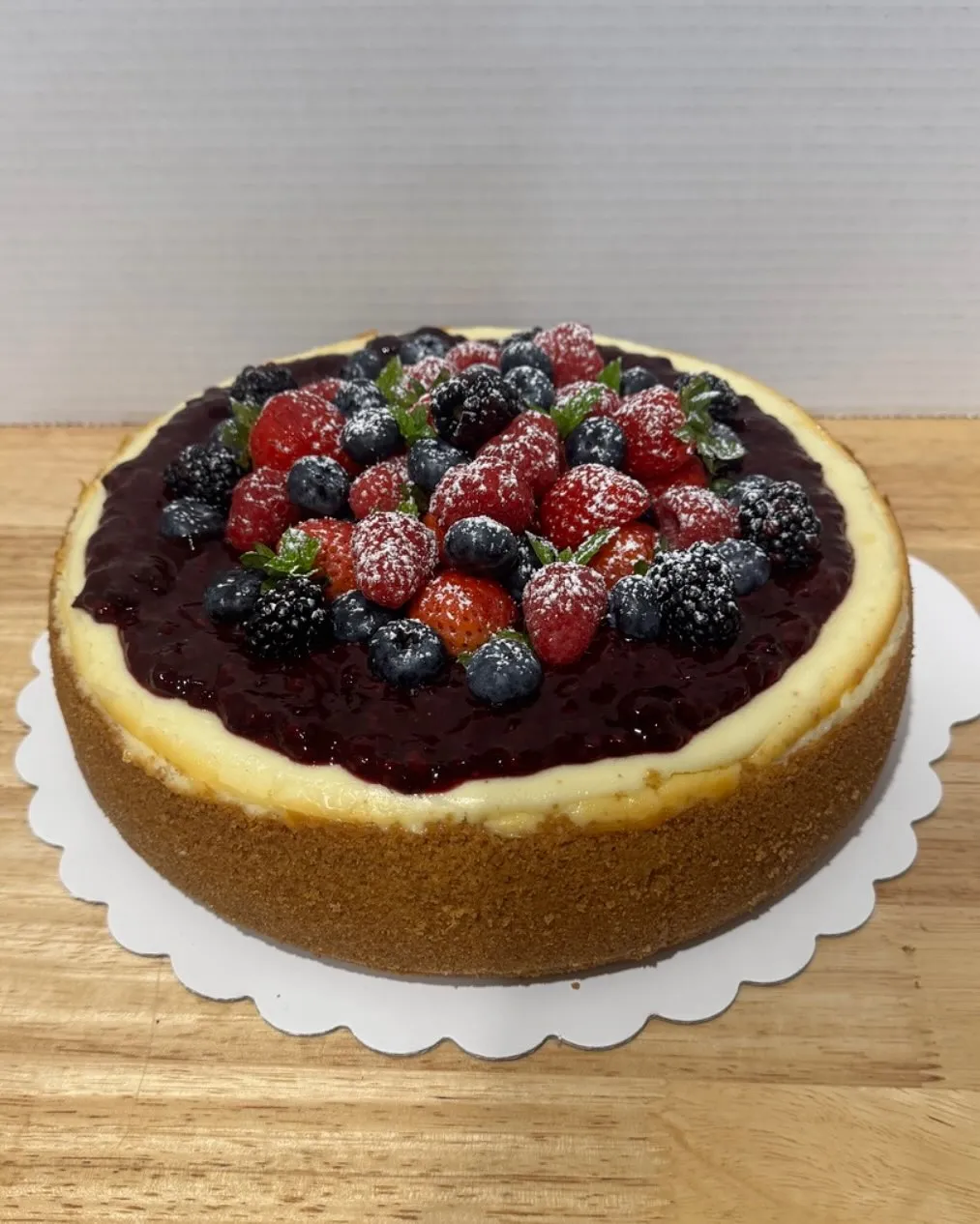 A mixed-berry cheesecake topped with strawberries, blueberries and blackberries over berry compote.