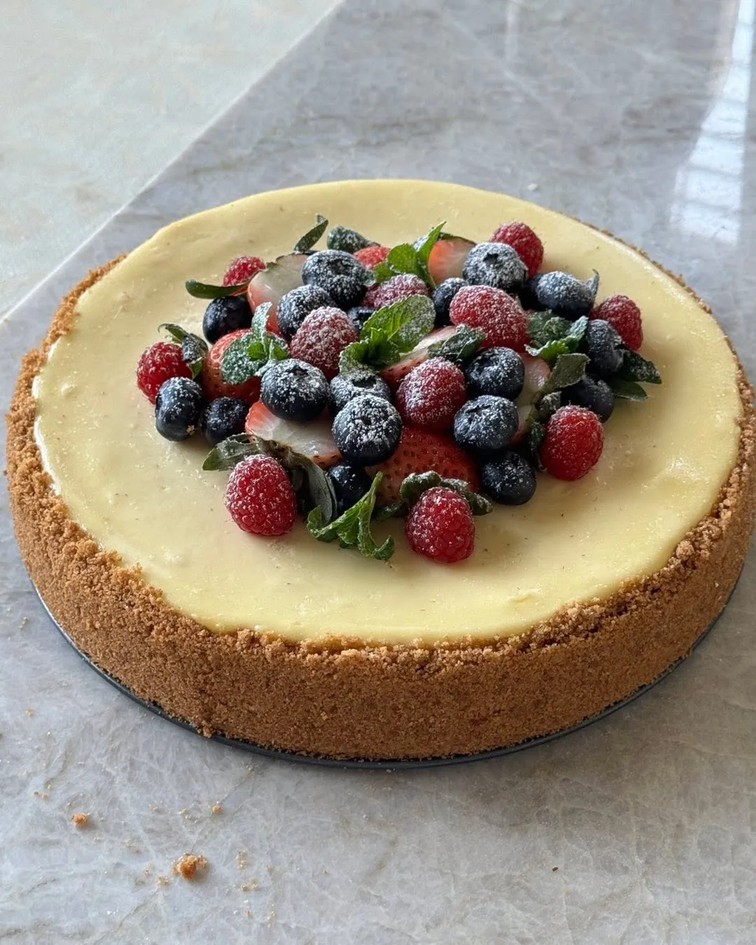 A classic cheesecake topped with fresh berries dusted with powdered sugar.