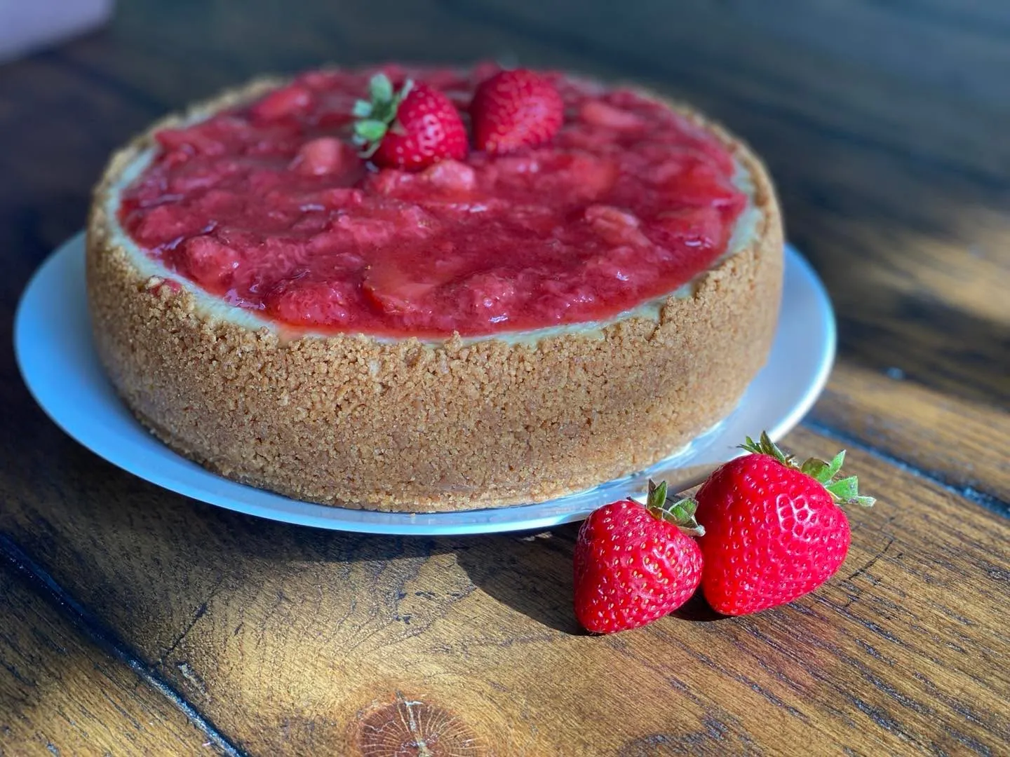 A creamy strawberry cheesecake topped with strawberry compote and fresh strawberries.