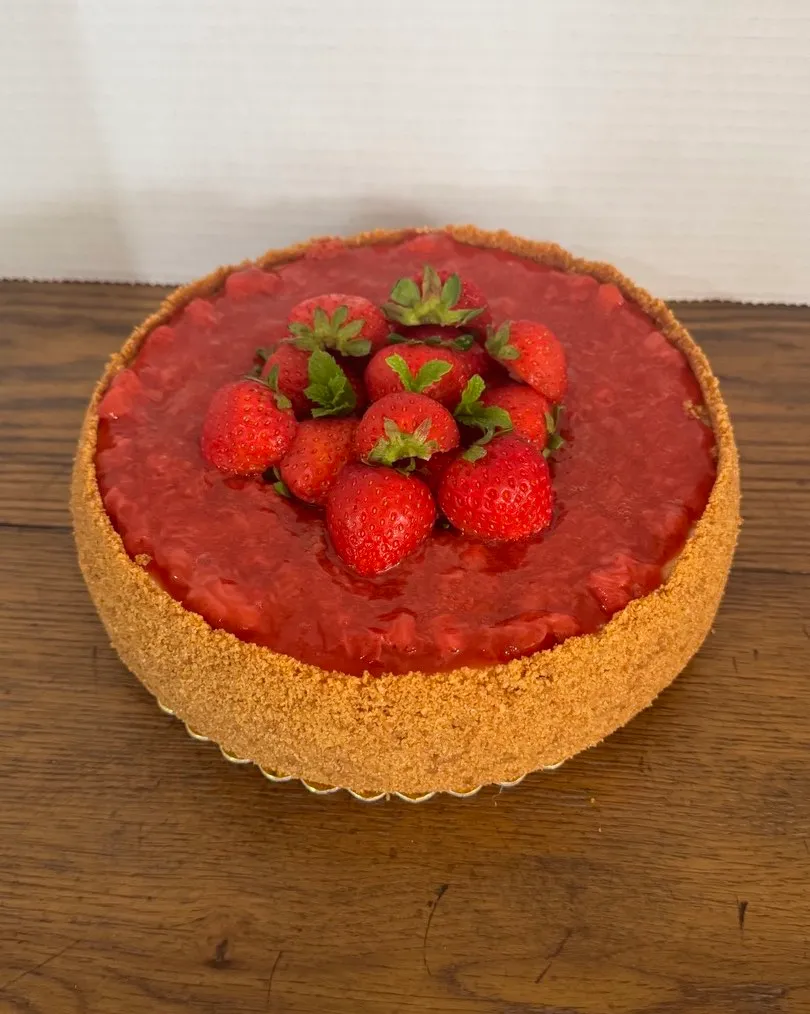 A strawberry cheesecake topped with strawberry glaze and fresh strawberries.