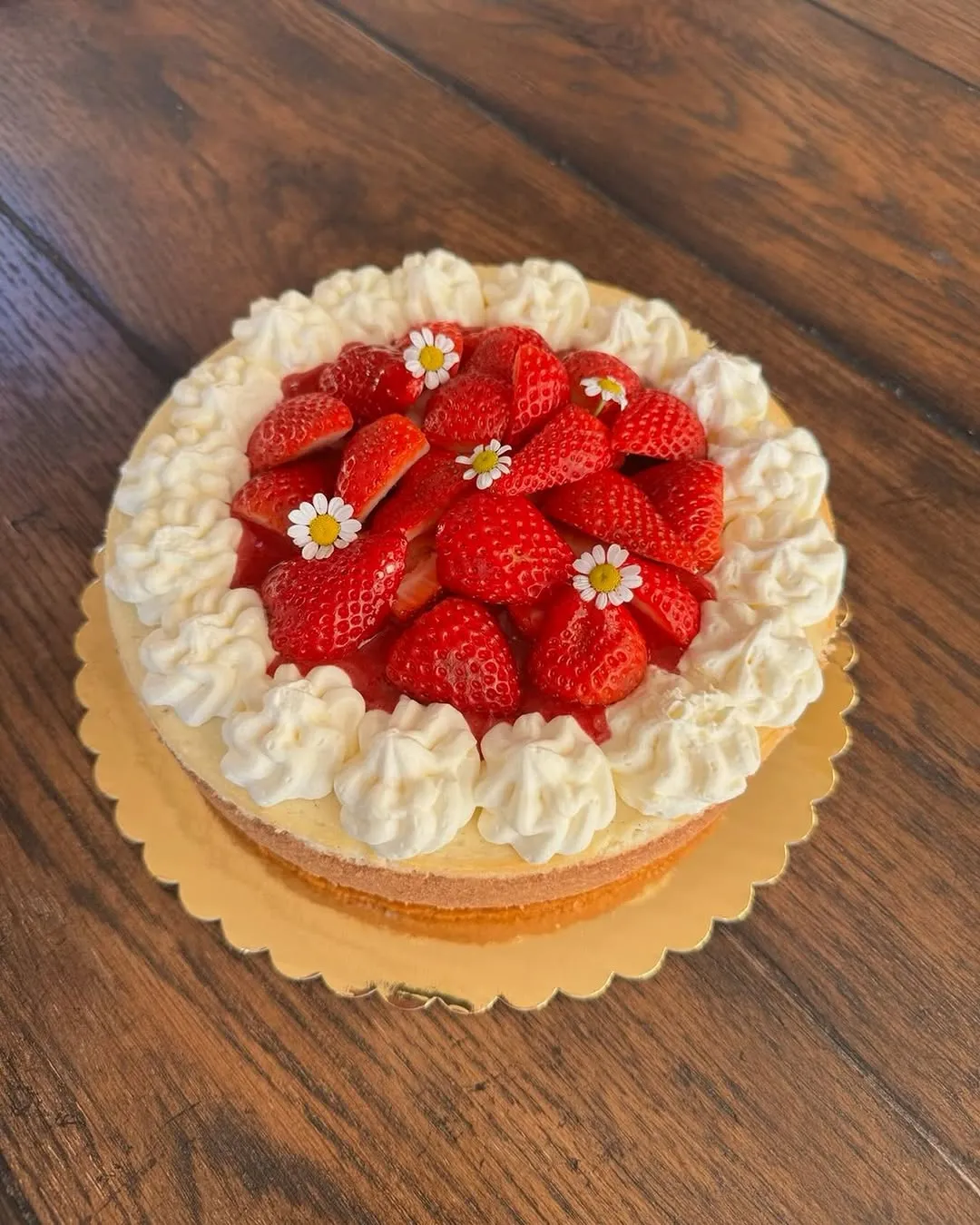 A strawberry cheesecake topped with fresh halved strawberries and whipped-cream rosettes.